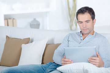 handsome man relaxing in sofa with tablet