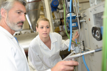 Obraz premium Man adjusting machine, lady looking on