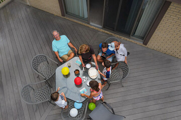 Aerial view of family and grandparents celebrating a birthday party outdoors on patio