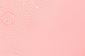 de-focused. Closeup of pink transparent clear calm water surface texture with ripples, splashes and bubbles. Trendy abstract summer nature background. Coral colored waves in sunlight.