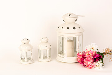Tres faroles blancos con ramo de flores rosas.