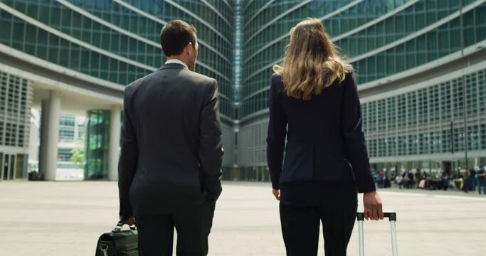 Cinematic shot of happy smiling business colleagues in formal apparel are walking satisfied with their work after leaving the offices. Concept of corporate, company, success, cooperation, teamwork.