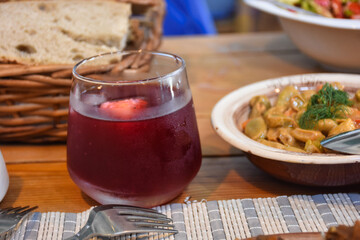 Iced black mulberry sherbet in a glass on the restaurant table and Aegean-style broad bean appetizer