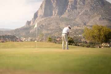 Golfer hitting ball on the green towards the hole