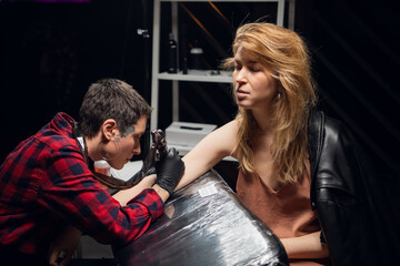 A young girl is excited about getting her first ever tattoo in a tattoo parlor with a stick and...