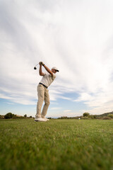 Golf player making a perfect swing on the golf course in the sunset.