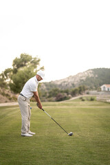 Golf player making a perfect swing on the golf course in the sunset.