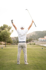 Golf player celebrating victory with his arms and his stick raised