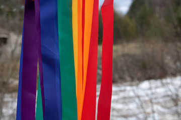 Bright rainbow ribbons on the background of a spring river.Carnival ribbons. LGBT symbol. Space for text