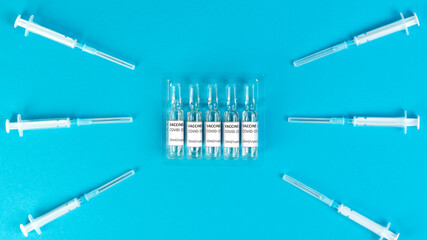 Coronavirus vaccine vials. Covid-19 vaccination with vaccine ampoules and syringes. Vaccine against the pandemic. Blue background. Stop Covid concept. Clinical trial.