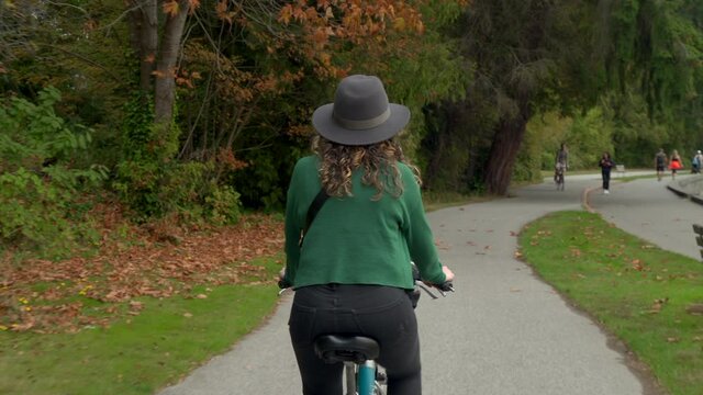 Cool Canadian girl wearing a hat cycling around Stanley Park during fall season in Vancouver, British Columbia, Canada.