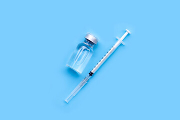 Bottle of vaccine and syringe on blue background with copy space. Covid-19 Coronavirus concept