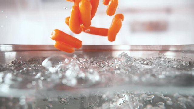 Frozen Baby Carrots Falling into Pot with Boiling Water in Macro and Slow Motion (Phantom Flex)