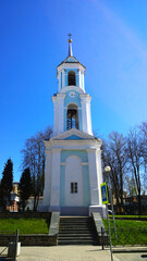 Fototapeta premium Two-tiered bell tower of Church of the Assumption of the Blessed Virgin Mary located in Pskov city, Russia. Ancient old building. Historical architecture. Blue sky. Travel destination. Vertical view.