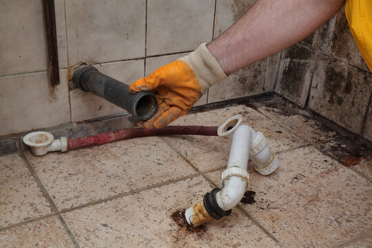 Plumber fixing old  and dirty plastic pipes for bathtube sink drain