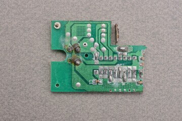 one green old plastic microcircuit with lead soldering lies on a gray table