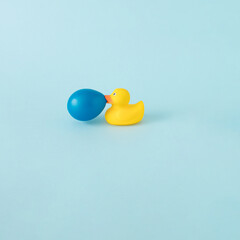 Yellow rubber duck with celtic blue bubble gum baloon against pastel background. Pop art concept.