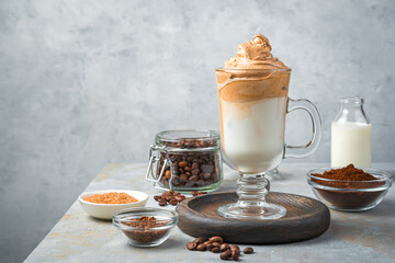Dalgona coffee and ingredients on a gray background.