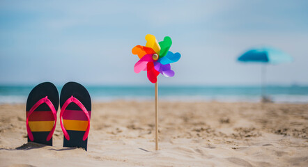 flip-flops next to a windmill with the colors of the rainbow and in the background an out-of-focus...