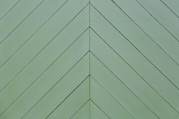 Wood texture. Fragment of a wall with a pattern of diagonal planks. The fence is painted in green. Rustic texture for background and design.
