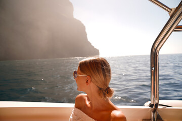 Joyful woman on sailing boat discovering island coast on summer cruise.
