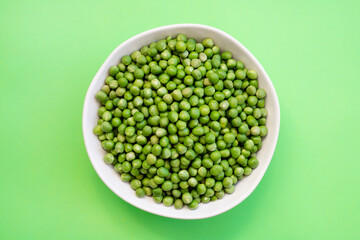 green peas in a bowl on green background.