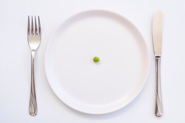 diet concept. one pea on an empty white plate