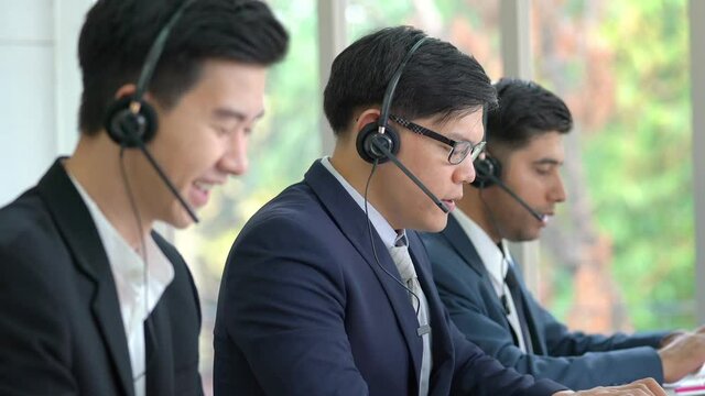 Diversity male customer service call center helpdesk team wearing headset speaking video call for online consulting and support client. Businessman working telesales marketing communication in office.