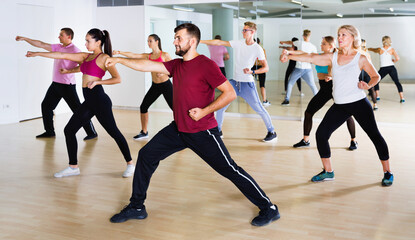 Fototapeta na wymiar Cheerful men women performing modern dance in fitness studio
