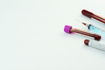 Vacuum tubes for collection and blood samples on white background..Transparent with purple and green cap and a syringe. Label to identify the data. Selective focus.