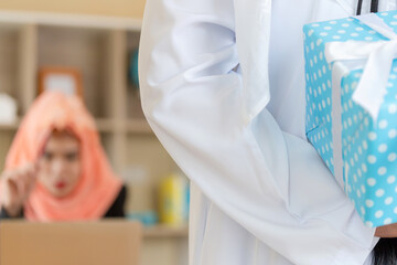 Muslim Arab man holding gift box on the hands with blurred girlfriend at office in office, Romantic surprise concepts