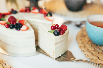 Cake decorated by berries and cup of tea. Delicious vegan dessert gluten, sugar, lactose free.