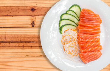 raw salmon red fish and vegetables on white plate with wooden background