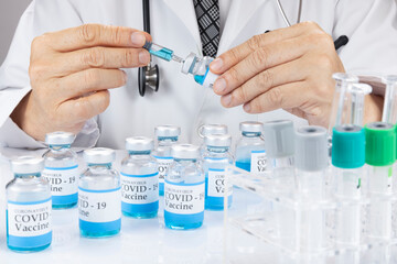 Fototapeta premium A doctor or a scientist in a laboratory coat holding a syringe with liquid vaccine vial.