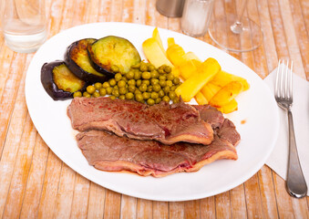 Roasted juicy beef with potatoes, eggplant and peas cooked in a restaurant