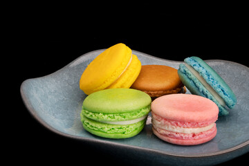 Colorful macaroons on blue ceramic plate.
