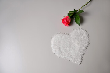 Bath salt and a small rose. Heart shape. Gray background
