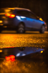 Reflection in water of a car passing on the street © Codrin Rusu/Wirestock