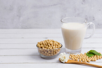 Soy and soy milk in a glass with soybeans in wooden bowl background