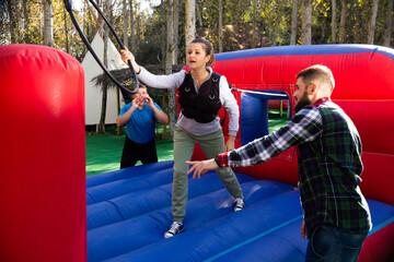 Excited male and female friends having fun passing obstacle course at adventure park