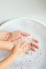 Women's and children's hands in white foam. Hygiene and cleanliness, skin care. High quality photo