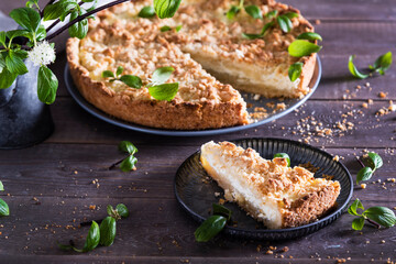 Beautiful and tasty curd pie on a wooden background surrounded by greenery. Spring breakfast, herbs, morning, homemade cakes. Selective focus.