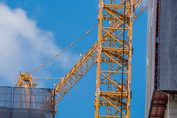 Closeup of large yellow industrial crane beside new construction.