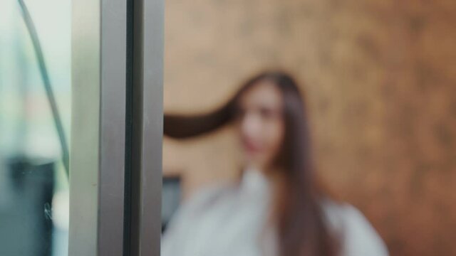 The barber is using scissors to trim the ends of the hair to a beautiful young clientele in a friendly atmosphere.