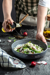 Rustic salad with radish, Cook hands sprinkling olive oil. Healthy vegan food. Food recipe background. Close up