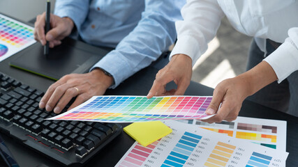 Graphic designer or creative working together coloring using graphics tablet and a stylus at desk...