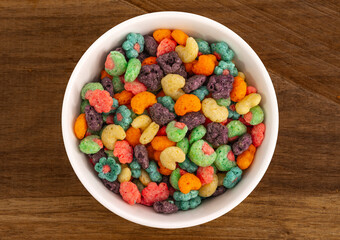Top view of bowl with fruit cereal naturally and artificially fruit flavored sweetened corn puffs. Cereal fruity shapes