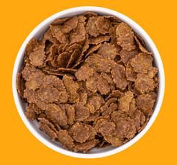 Top view of bowl with sweet chocolate cereal flakes for breakfast on white wooden background