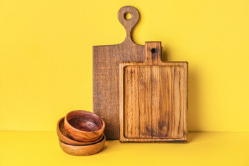 Chopping boards and bowls on color background