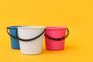 Plastic buckets on color background